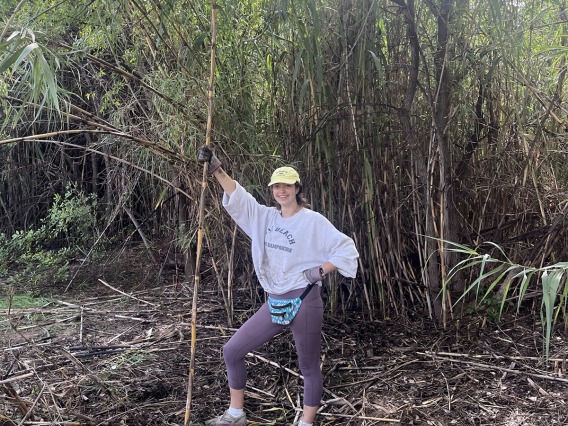 Nicole Collins stands next to foliage while volunteering.