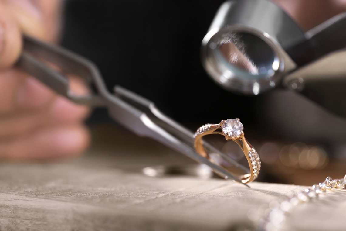 Close-up view of a diamond ring being examined using a jeweler's loupe