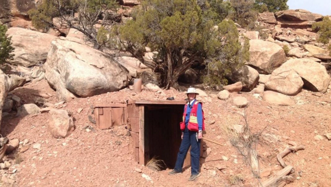A woman stands in front of a mine entrance
